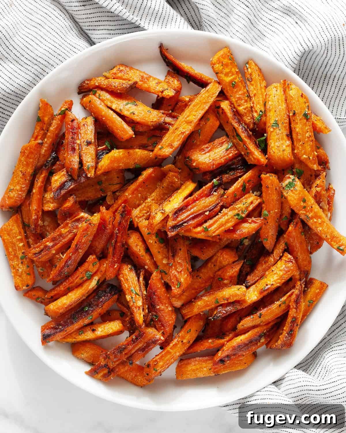 Roasted Carrots with Garlic and Parmesan 2 A close-up shot of perfectly roasted garlic parmesan carrots, beautifully arranged on a white plate, showcasing their golden-brown edges and melted cheese.