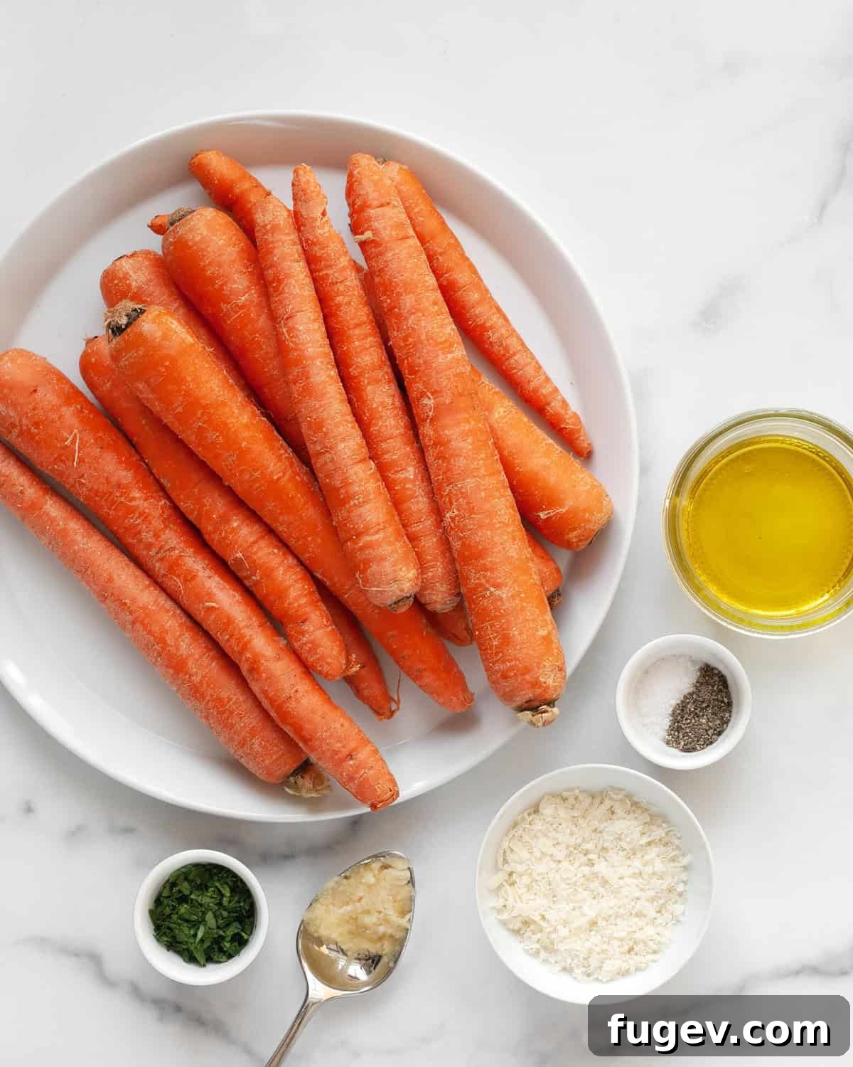 Roasted Carrots with Garlic and Parmesan 3 Fresh ingredients laid out on a wooden board, including bright orange carrots, whole garlic cloves, a wedge of Parmesan cheese, and fresh parsley sprigs, alongside olive oil, salt, and pepper.