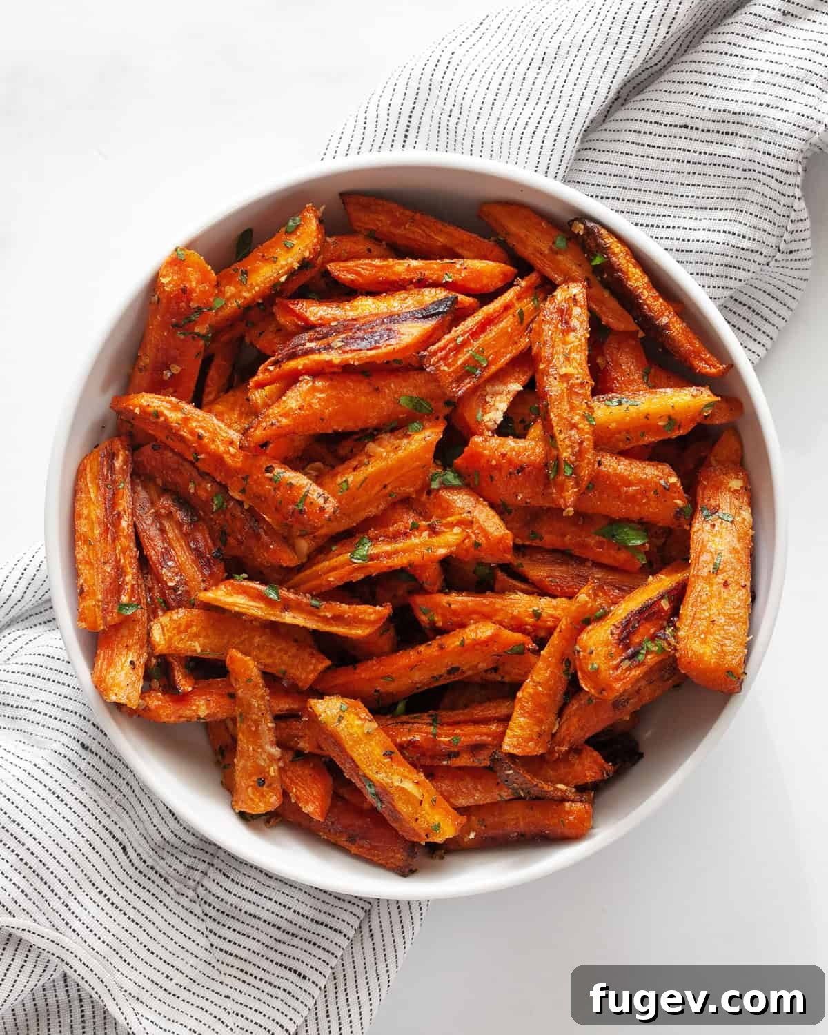 Roasted Carrots with Garlic and Parmesan 7 A bowl filled with freshly roasted garlic parmesan carrots, garnished with green herbs, ready to be served.