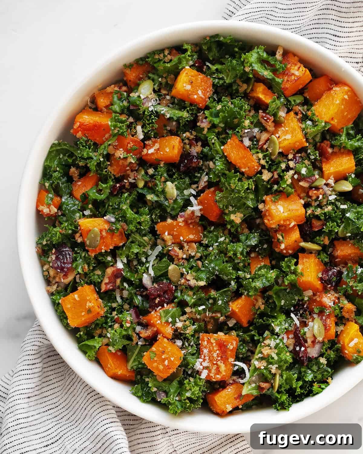 Harvest Roasted Butternut Squash Salad 2 A vibrant roasted butternut squash salad generously filled in a large rustic bowl, showcasing golden squash cubes, green kale, red cranberries, and crunchy seeds.