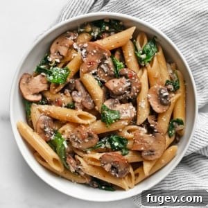A close-up shot of mushroom spinach pasta in a bowl, garnished with fresh parsley.