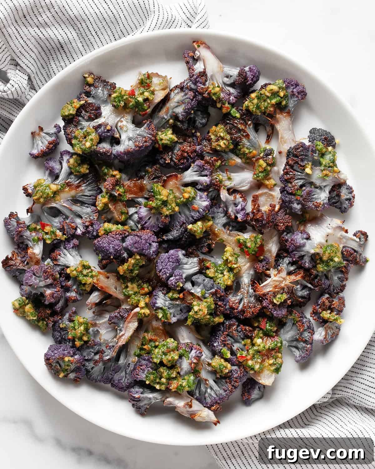 Roasted Amethyst Florets with Zesty Cilantro Burst 2 Roasted purple cauliflower on a serving plate, generously drizzled with a vibrant green cilantro pesto.