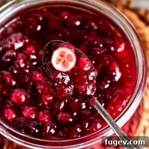 A halved cranberry in sauce showing its tart interior and vibrant red hue.