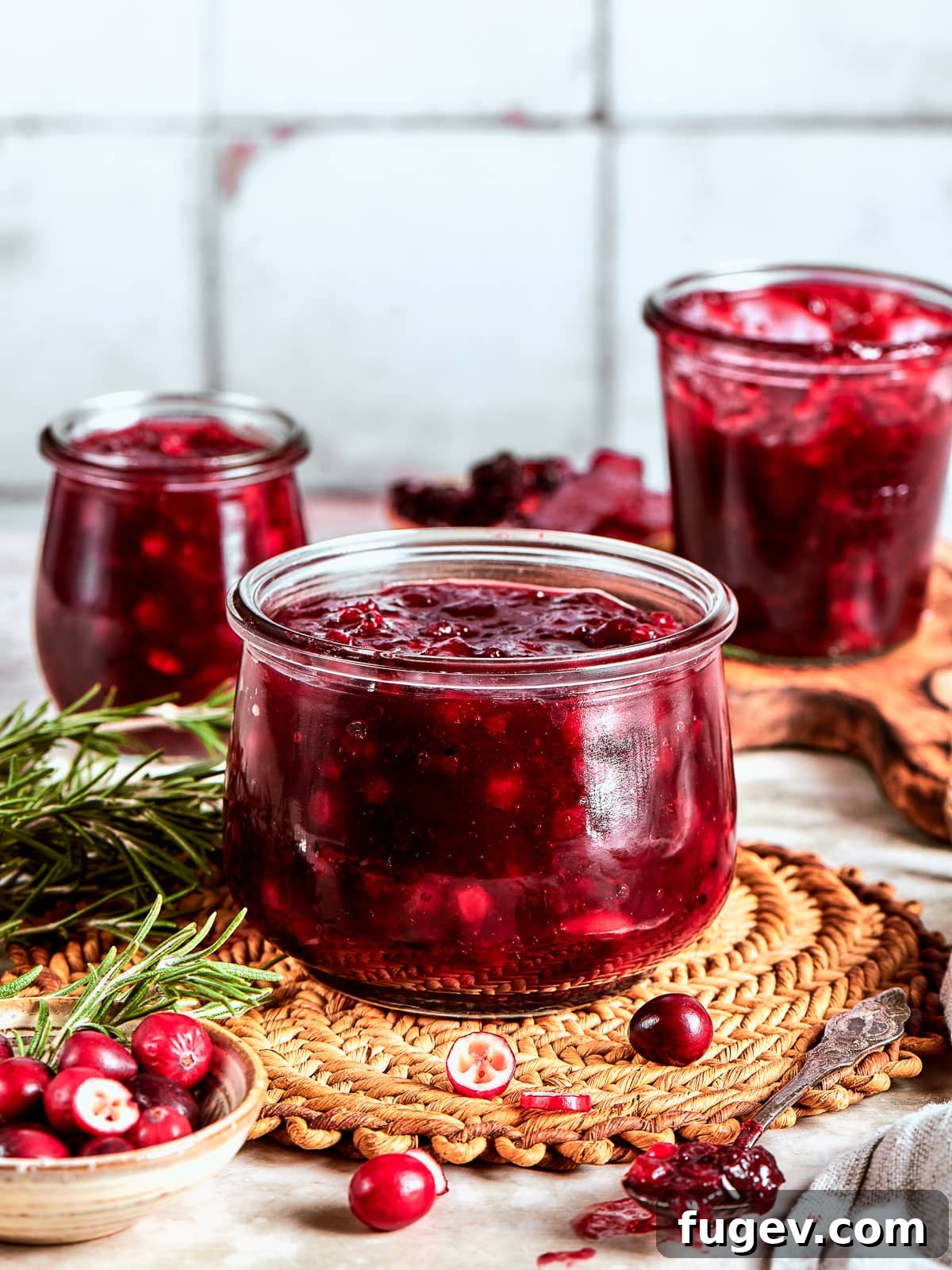 Holiday Cranberry Jewel 10 Three elegant glass jars of homemade cranberry sauce cooling on the kitchen counter, ready to be stored in the fridge or given as thoughtful gifts.