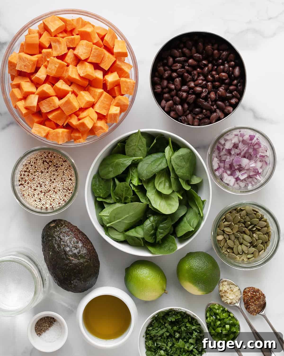 Spiced Roasted Sweet Potato & Black Bean Bowl 3 Various fresh ingredients laid out, including sweet potatoes, black beans, avocado, red onions, quinoa, spinach, pumpkin seeds, limes, garlic, oil, and cilantro, ready for the Roasted Sweet Potato Black Bean Salad.