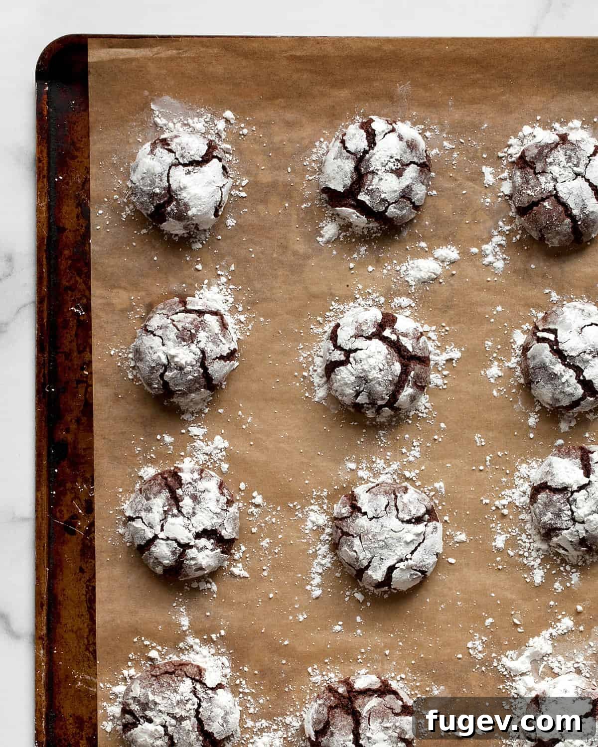 Fudgy Crinkle Delights 8 Baked crinkle cookies on a sheet pan.