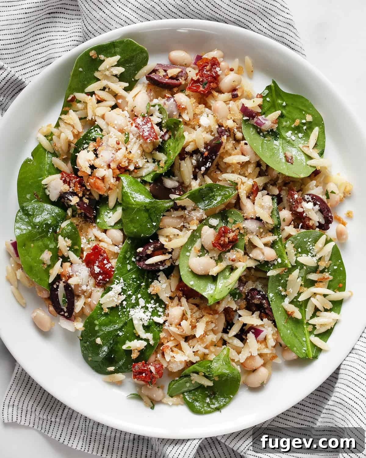 Lemony Orzo Delight 7 A close-up of lemon orzo pasta salad served on a white plate, garnished with fresh herbs, showcasing its vibrant colors and textures.