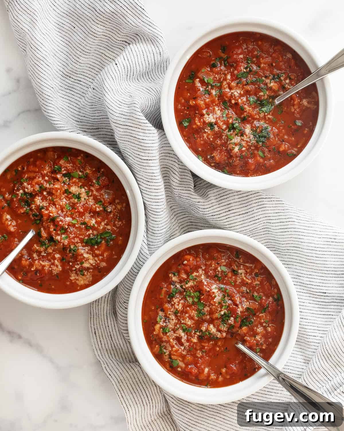 Wholesome Tomato Rice Warmth 2 Three bowls of tomato rice soup, garnished with fresh herbs and Parmesan.