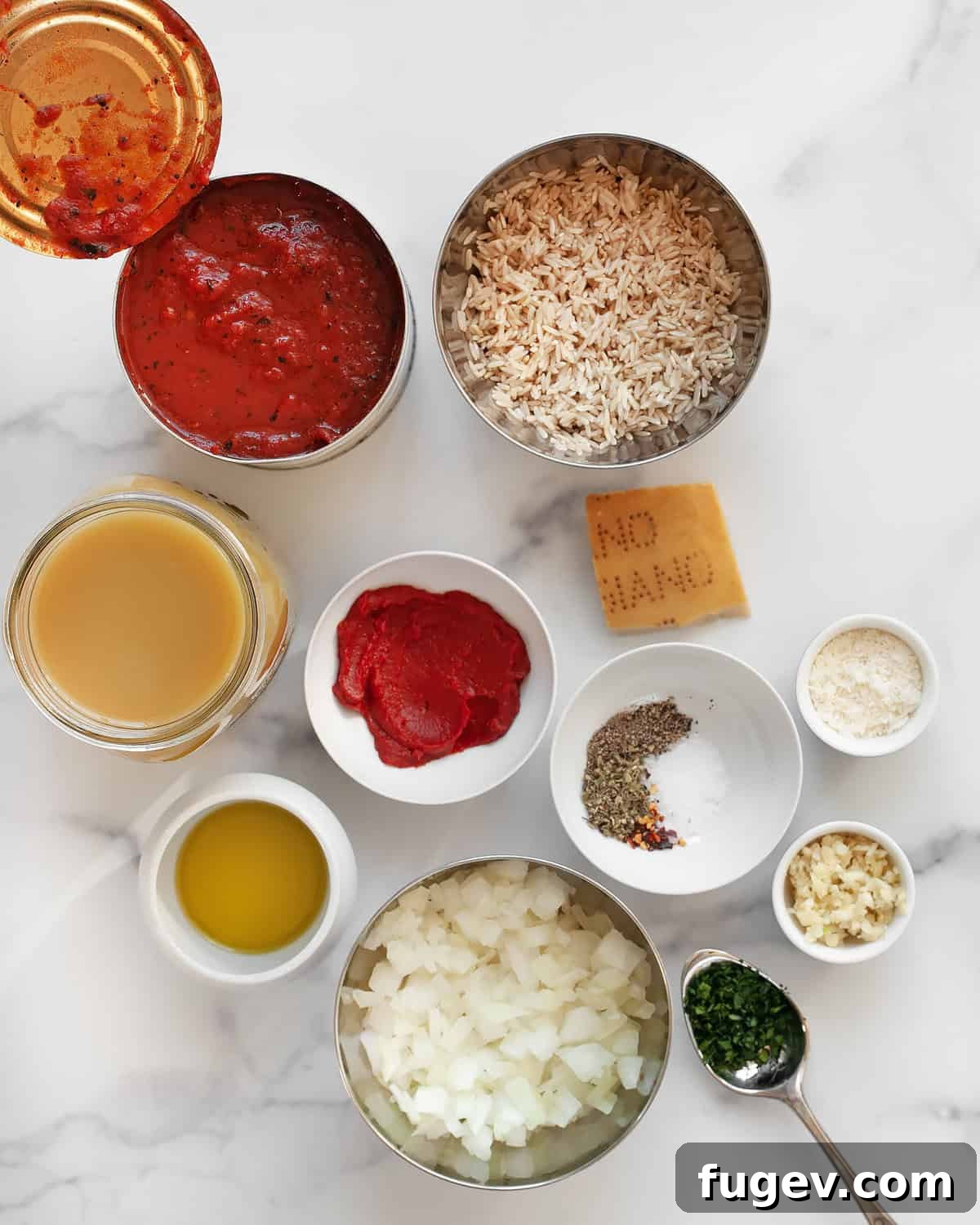 Wholesome Tomato Rice Warmth 3 Ingredients including crushed tomatoes, brown rice, garlic, onions, spices, parmesan rind, tomato paste, olive oil and vegetable broth laid out on a table.