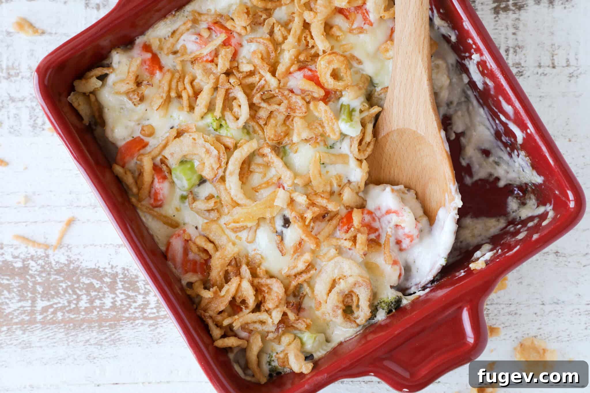 Hearty Vegetable Bake 4 A vibrant baked vegetable casserole, fresh from the oven, served in a red dish with a perfect golden crust and crunchy fried onions on top.