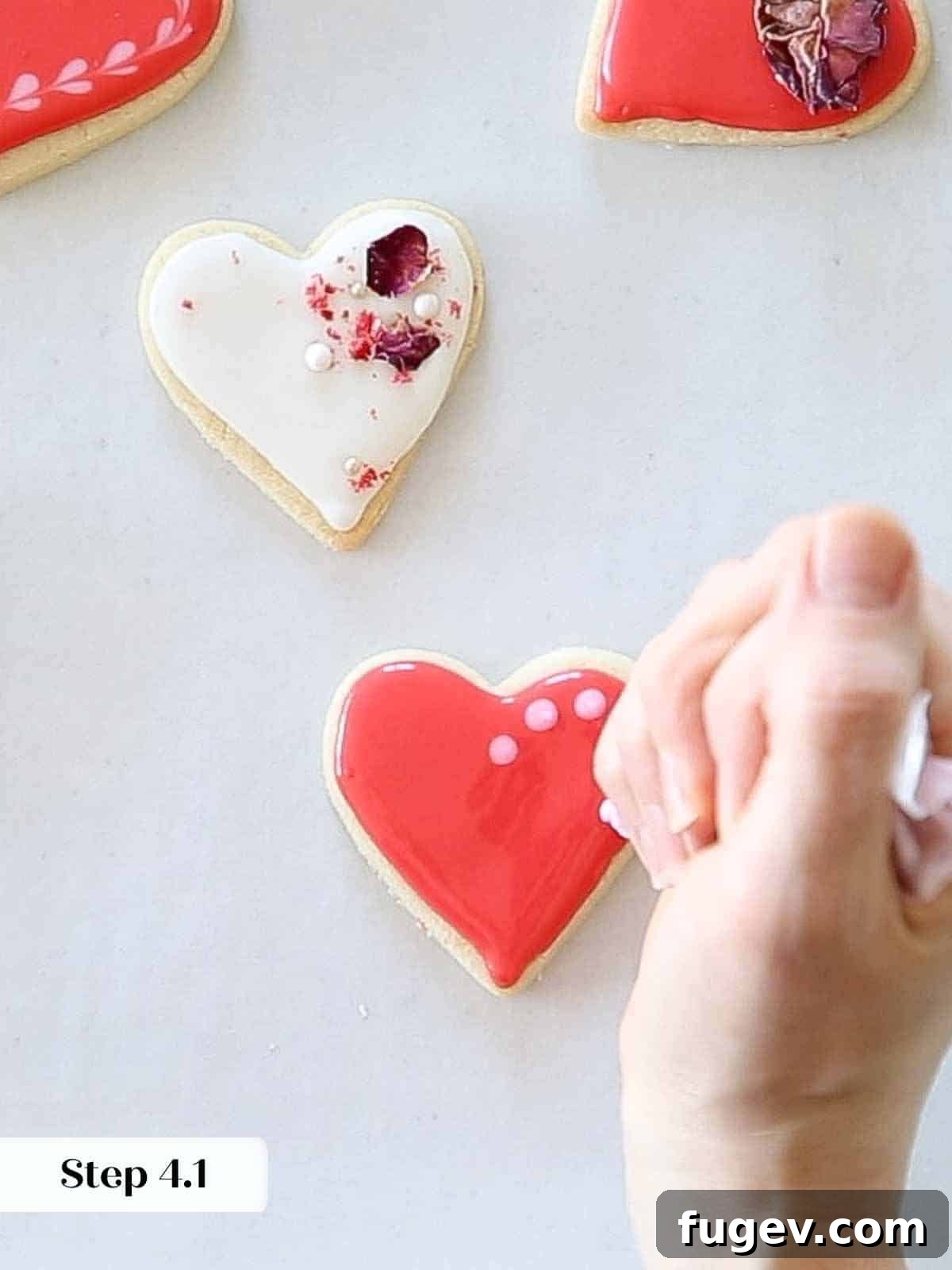 Cupid's Confections 14 Adding small light pink dots onto vibrant red royal icing to create a pattern.