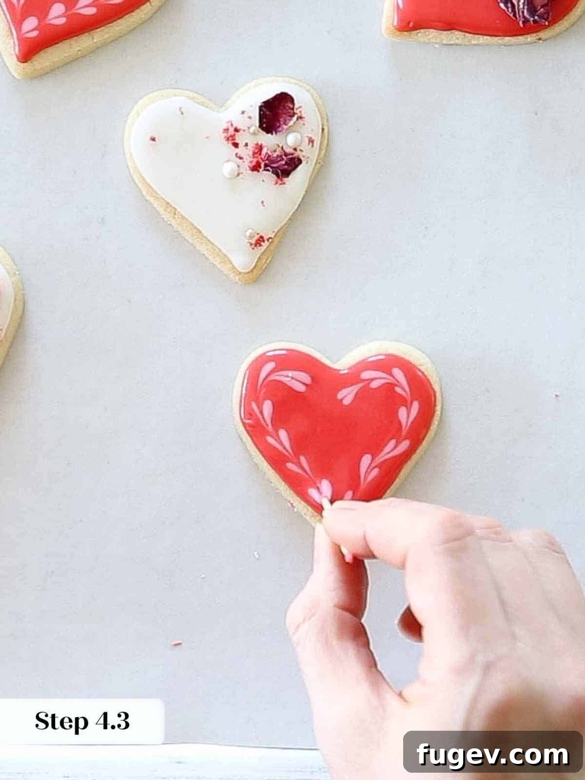 Cupid's Confections 16 The process of elegantly creating small pink hearts on a cookie with a toothpick.