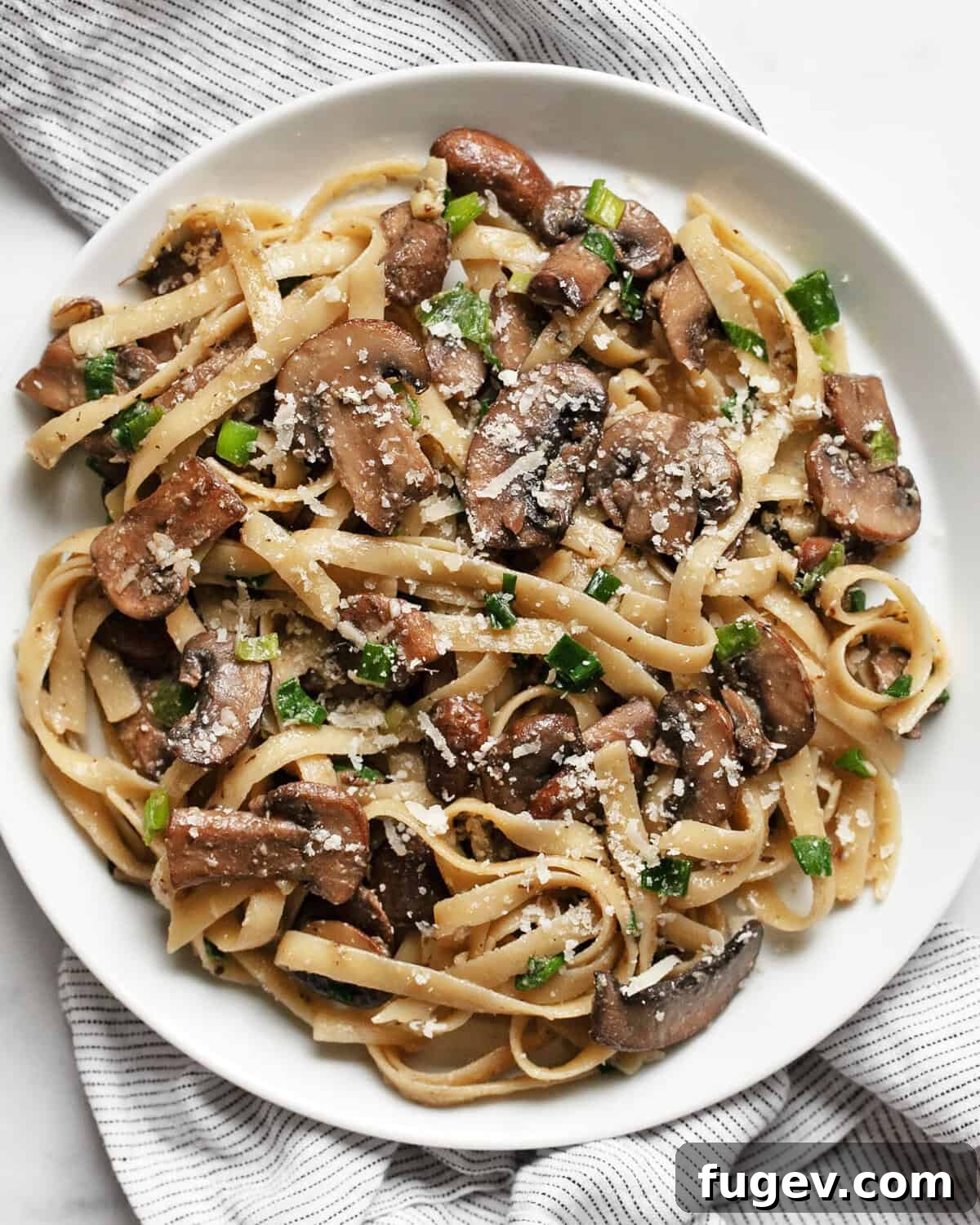 Umami-Packed Miso Mushroom Pasta 2 A bowl of creamy miso mushroom pasta garnished with fresh herbs and a sprinkle of parmesan cheese, ready to be served.