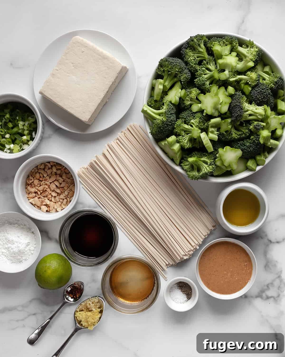 Crispy Roasted Tofu and Broccoli Power Bowls 3 A flat lay image displaying all the ingredients for roasted broccoli tofu bowls: tofu, broccoli, udon noodles, scallions, peanuts, garlic, ginger, peanut butter, soy sauce, and lime.
