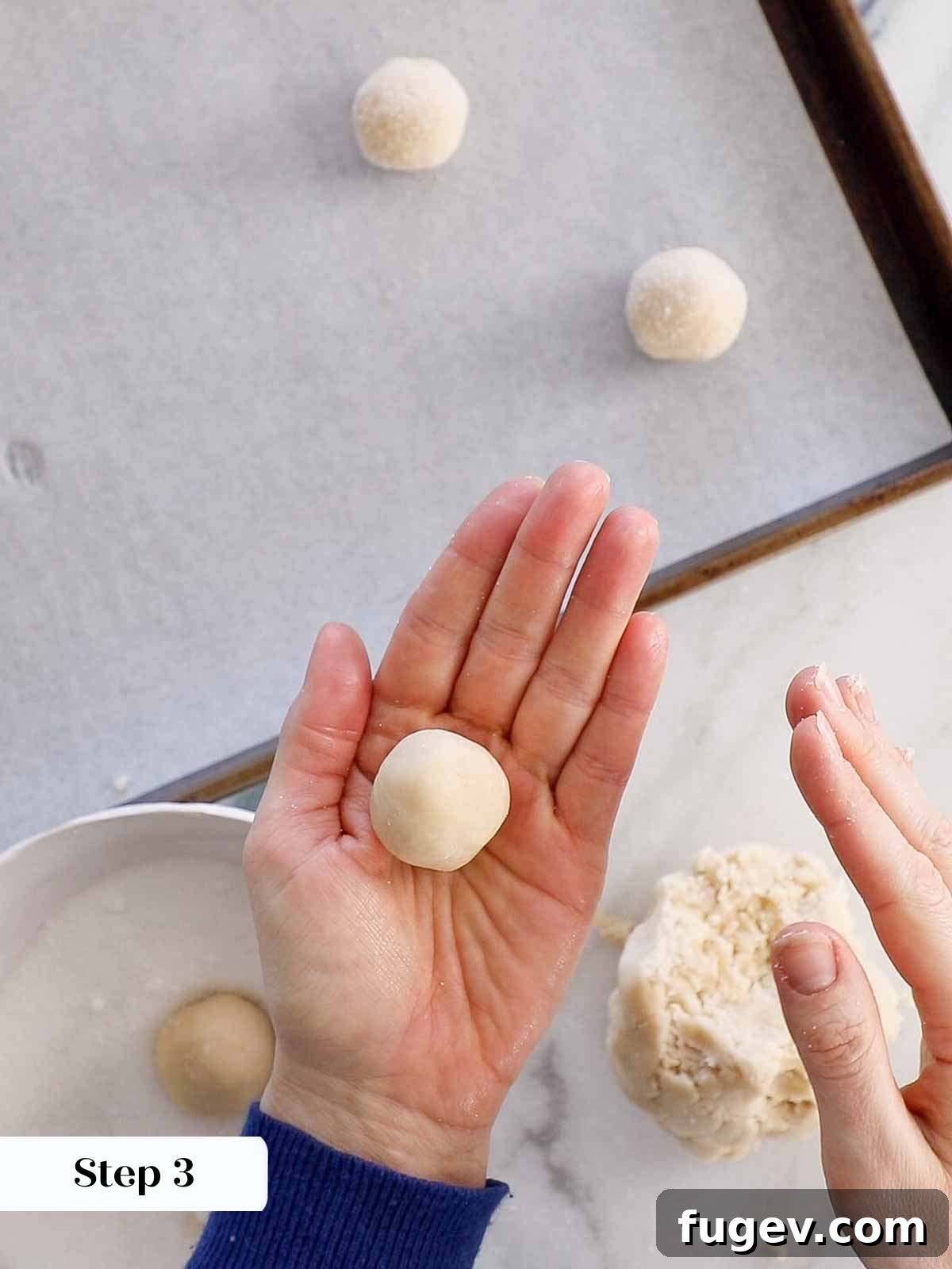 Perfectly Jammed Thumbprints 6 Hands carefully rolling a piece of cookie dough into a smooth, round ball. The focus is on the shaping process.