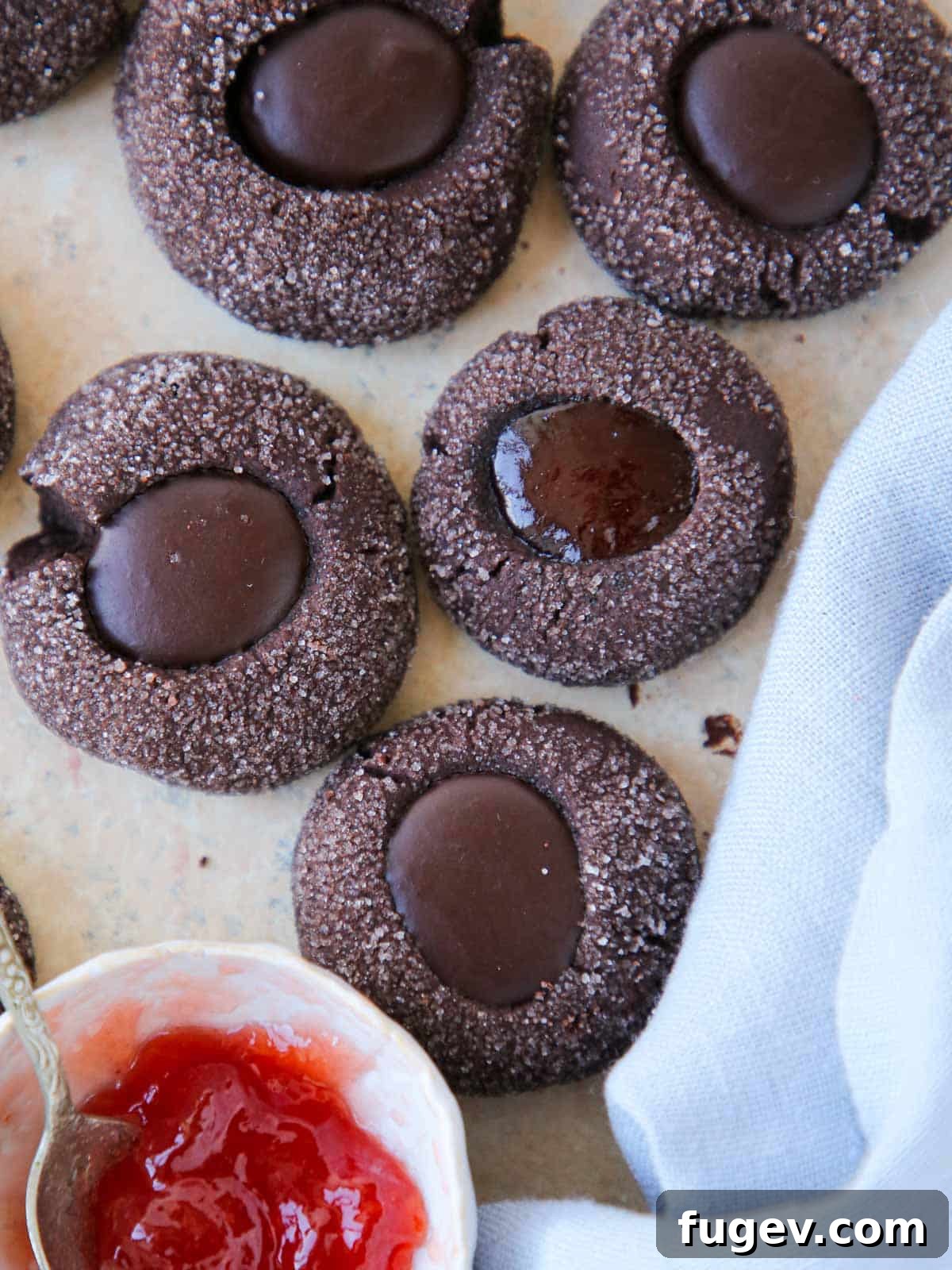 Velvety Chocolate Thumbprint Wonders 2 Assorted chocolate thumbprint cookies, some filled with rich chocolate ganache and others with bright raspberry jam, elegantly arranged on a serving plate.
