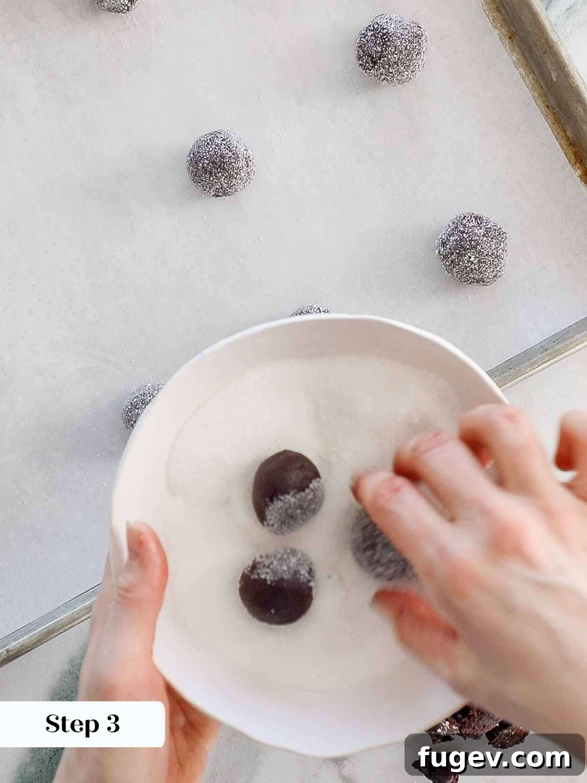 Velvety Chocolate Thumbprint Wonders 9 Cookie dough balls being rolled in granulated sugar for a sparkling coating.