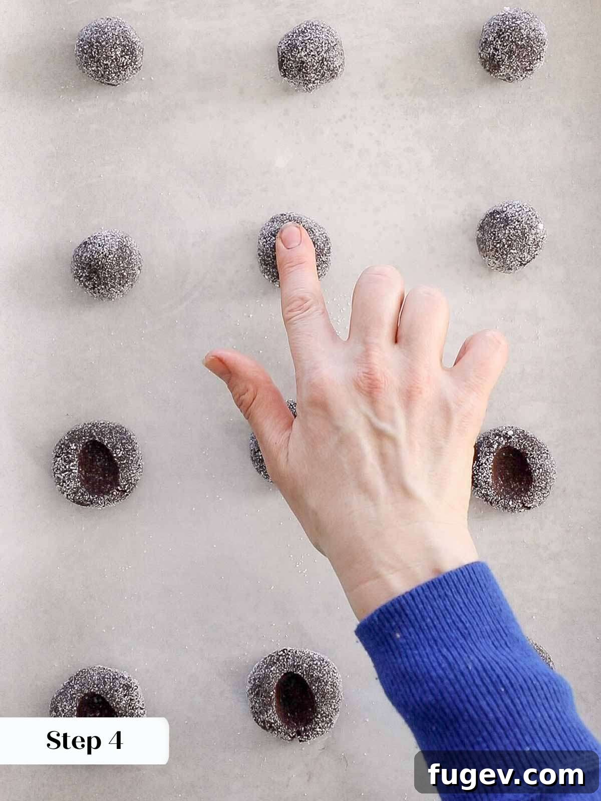 Velvety Chocolate Thumbprint Wonders 10 Creating perfect thumbprint indentations in raw chocolate cookie dough on a baking sheet.