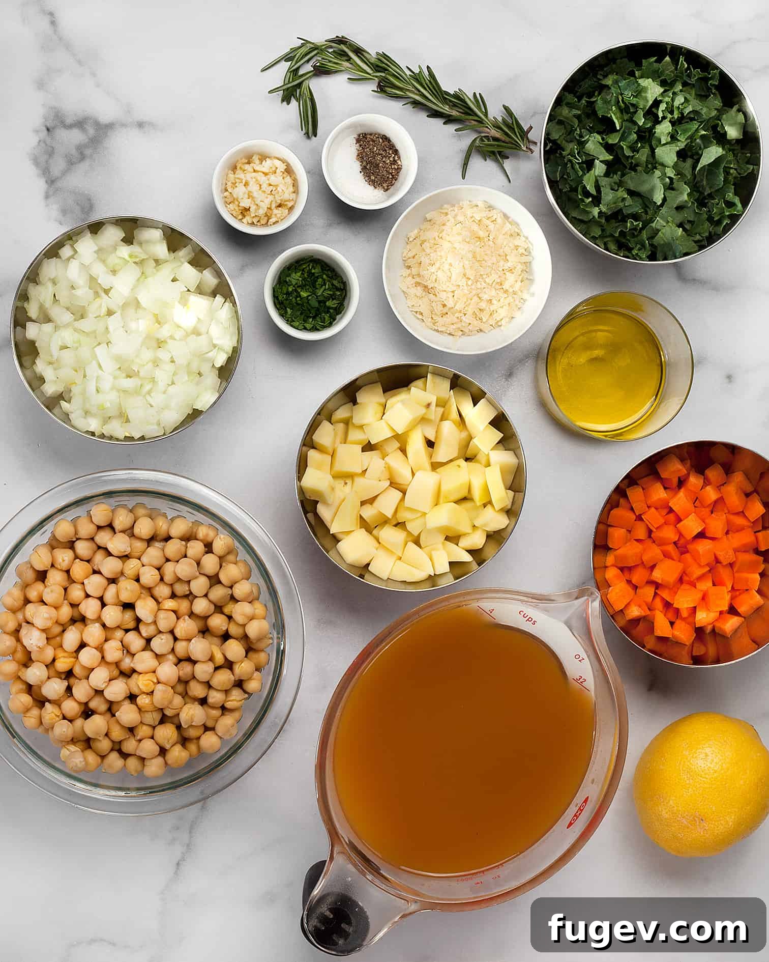 Simple Savory Chickpea Soup 3 A flat lay image of all the fresh ingredients needed for chickpea soup, including canned chickpeas, carrots, potatoes, kale, vegetable broth, onions, garlic, and rosemary.