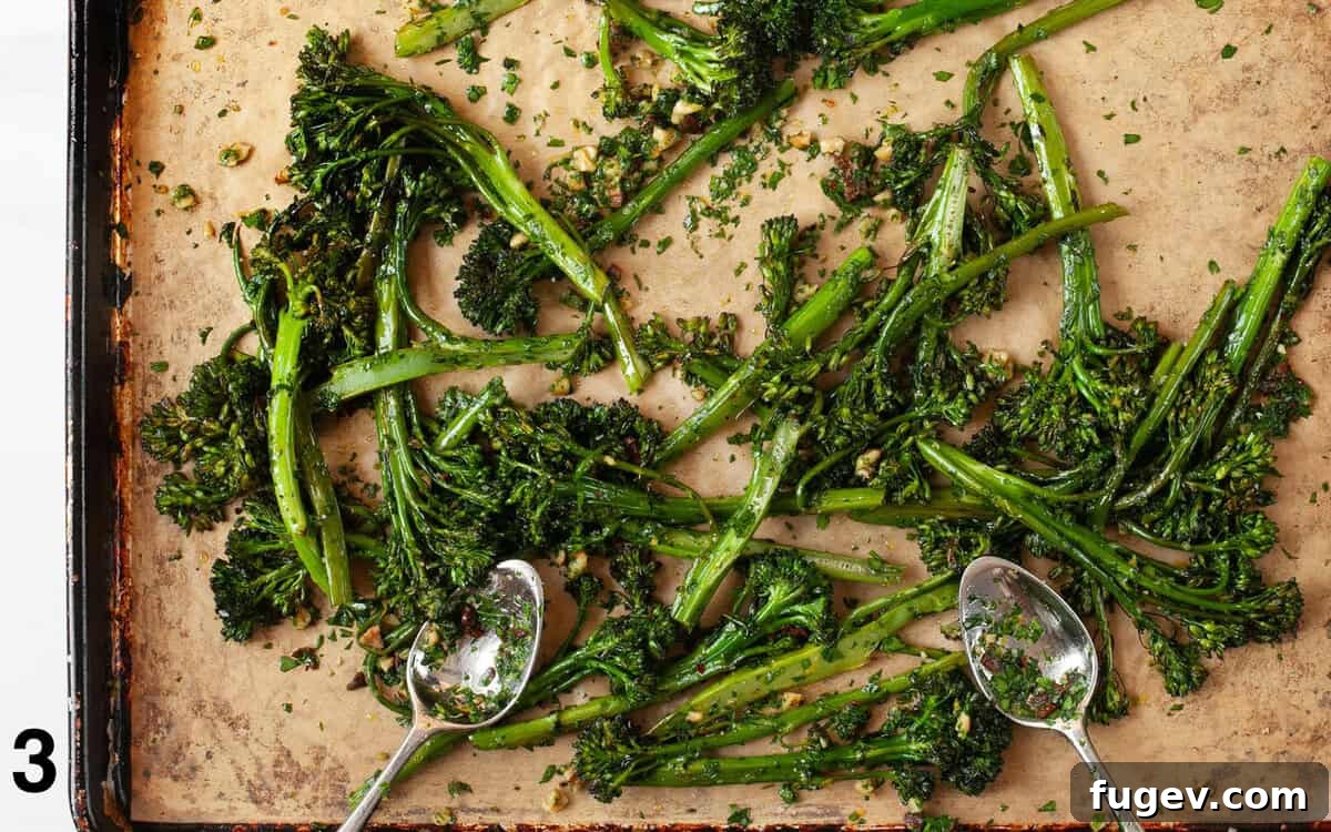 Crisp Roasted Broccolini with Sun Kissed Tomato Gremolata 5 Roasted broccolini being tossed with sun-dried tomato gremolata on a parchment-lined sheet pan.