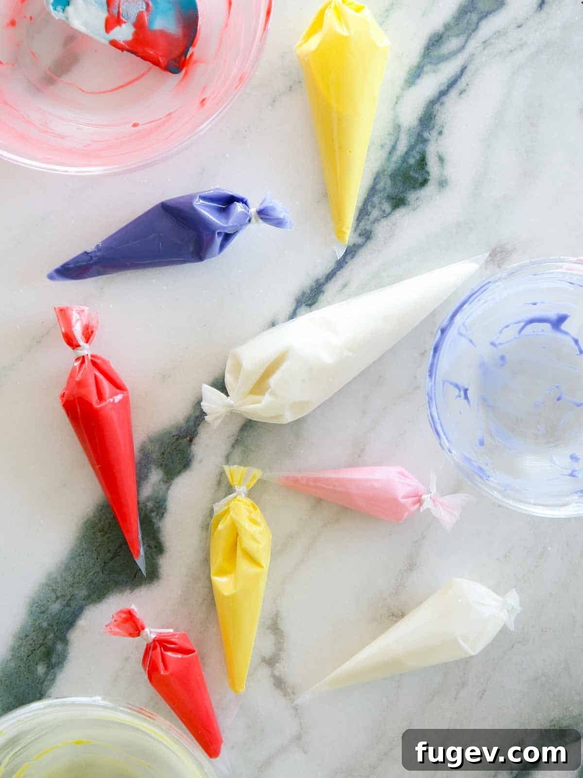Foolproof Royal Icing with Meringue Powder 12 Several piping bags filled with different colors of royal icing, neatly arranged on a marble surface, ready for various decorating tasks.