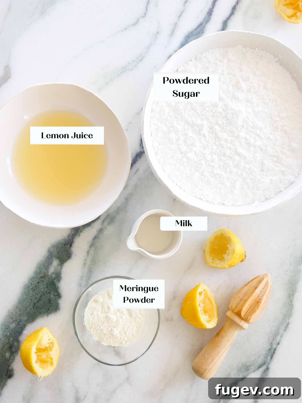 Foolproof Royal Icing with Meringue Powder 4 A flat lay of royal icing ingredients, including meringue powder, fresh lemons, powdered sugar, and milk, on a sleek marble surface.