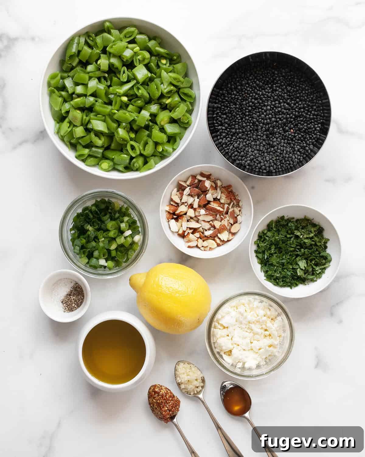 Crunchy Snap Pea and Lentil Delight 3 A flat lay photograph showcasing all the fresh ingredients for the snap pea lentil salad: chopped snap peas, cooked black lentils, almonds, fresh herbs, scallions, lemon, feta cheese, garlic, mustard, olive oil, and honey.