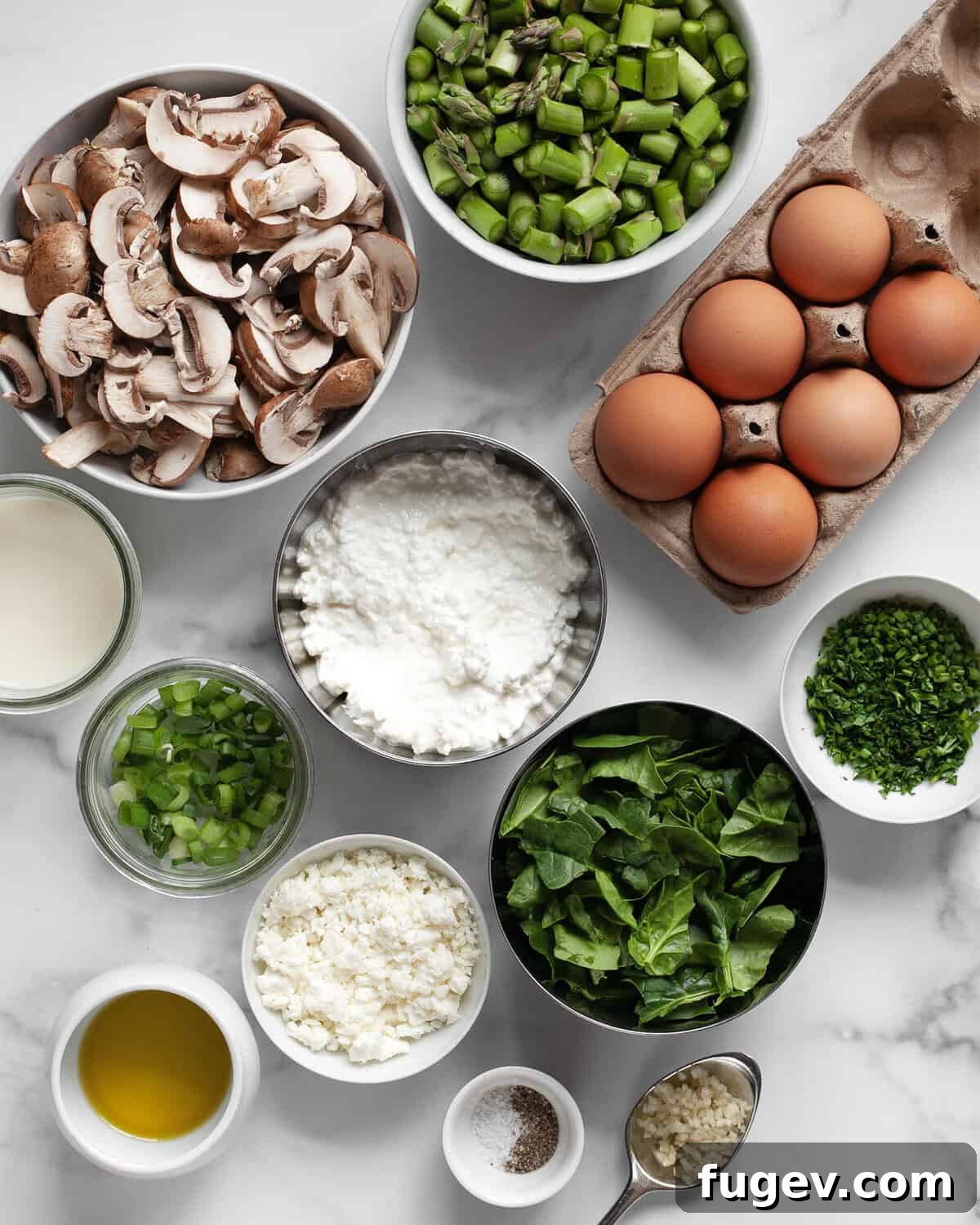 Roasted Asparagus and Creamy Cottage Cheese Frittata 3 A vibrant display of fresh ingredients for the egg bake, including eggs, crisp asparagus, earthy mushrooms, bright scallions, aromatic garlic, creamy milk, salty feta, and fresh parsley and chives.