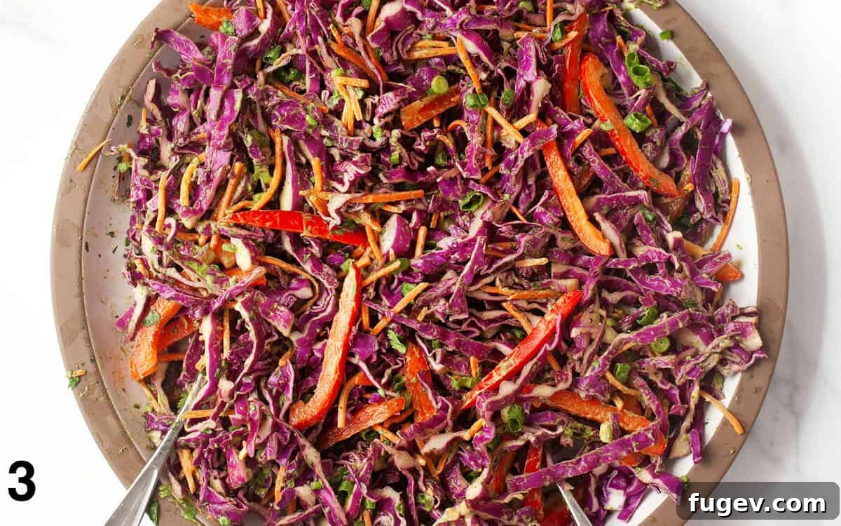 Vibrant Red Cabbage Slaw 5 A large glass bowl filled with vibrant red cabbage slaw, perfectly tossed with the creamy avocado lime dressing, ready to be served.
