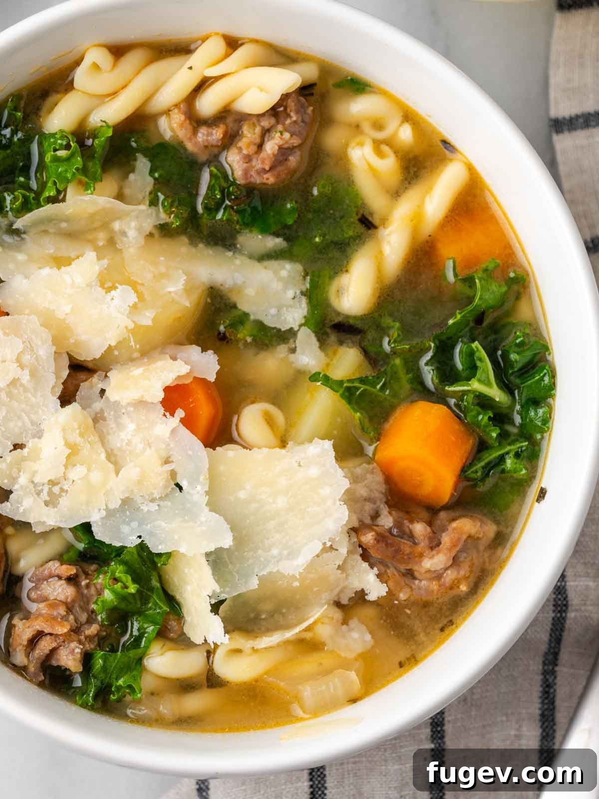 Hearty Italian Sausage Soup 2 A vibrant bowl of Italian sausage soup topped with freshly shaved Parmesan cheese and ribbons of fresh kale.