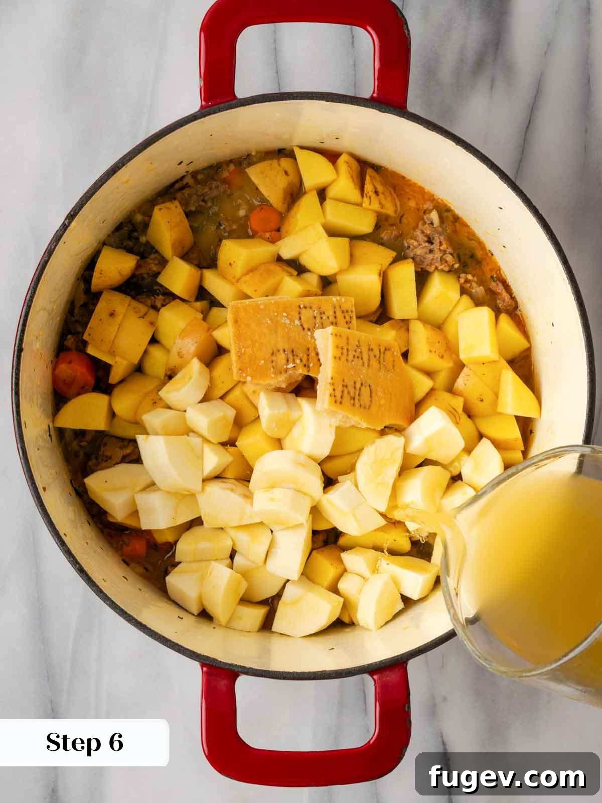 Hearty Italian Sausage Soup 8 Pouring rich, homemade brown chicken stock into the pot, combining with the sautéed sausage and vegetables to create the base of the savory Italian sausage soup.
