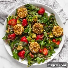 Strawberry salad with pistachio-crusted goat cheese on a plate.