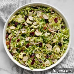 Shaved brussels sprout salad with cranberries, almonds and parmesan in a large bowl.