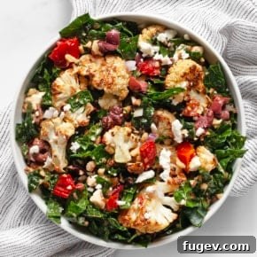 Kale salad with roasted cauliflower, tomatoes, and olives in a bowl.