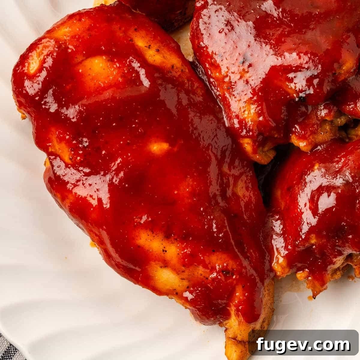 Perfect Backyard BBQ Chicken 3 chicken breast on white plate with bbq sauce.