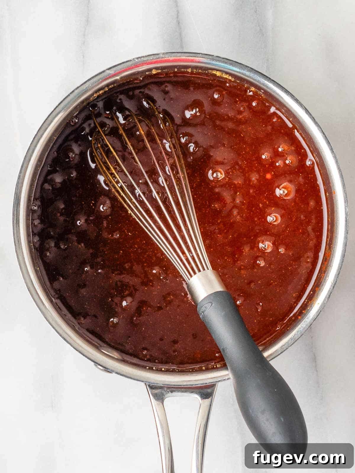 Simple Homemade BBQ Sauce 2 Homemade BBQ sauce simmering in a small pot with a whisk nearby, ready to be enjoyed.