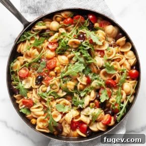 One pan orecchiette pasta dish in a large skillet, featuring chickpeas and olives.