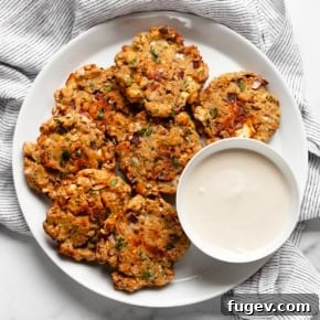 Baked chickpea fritters on a plate, served with a small bowl of lemon tahini sauce.