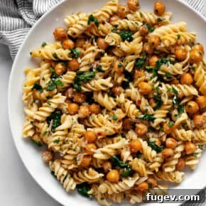 Chickpea pasta with sautéed spinach and garlic on a white plate.
