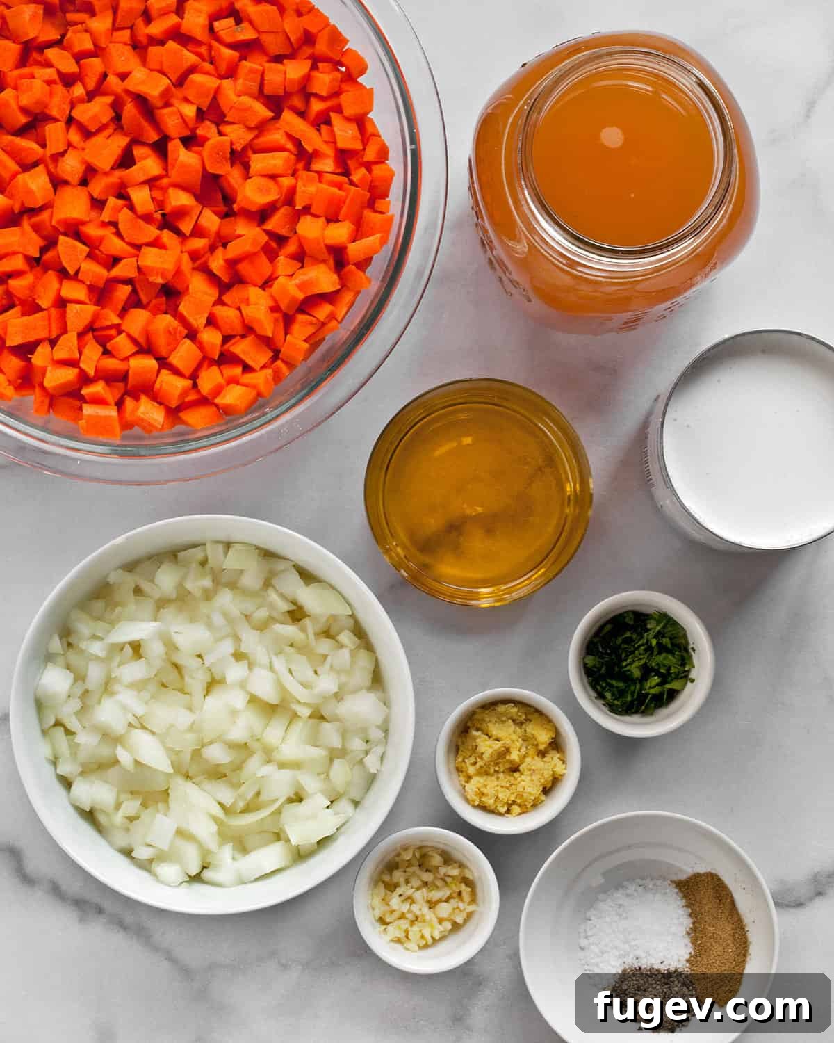 Golden Ginger Carrot Elixir 3 A flat lay of fresh ingredients for carrot ginger soup, including vibrant orange carrots, knobby ginger root, garlic cloves, a white onion, a bottle of olive oil, spices, and a can of coconut milk.