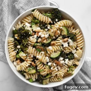 Roasted broccolini and zucchini pasta salad with walnuts and feta on a plate.