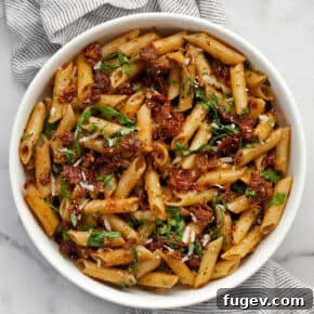 Pasta with sun dried tomatoes and arugula in a bowl