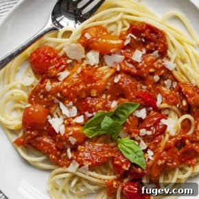 Tomato sauce spooned over spaghetti and topped with Parmesan and fresh basil leaves.