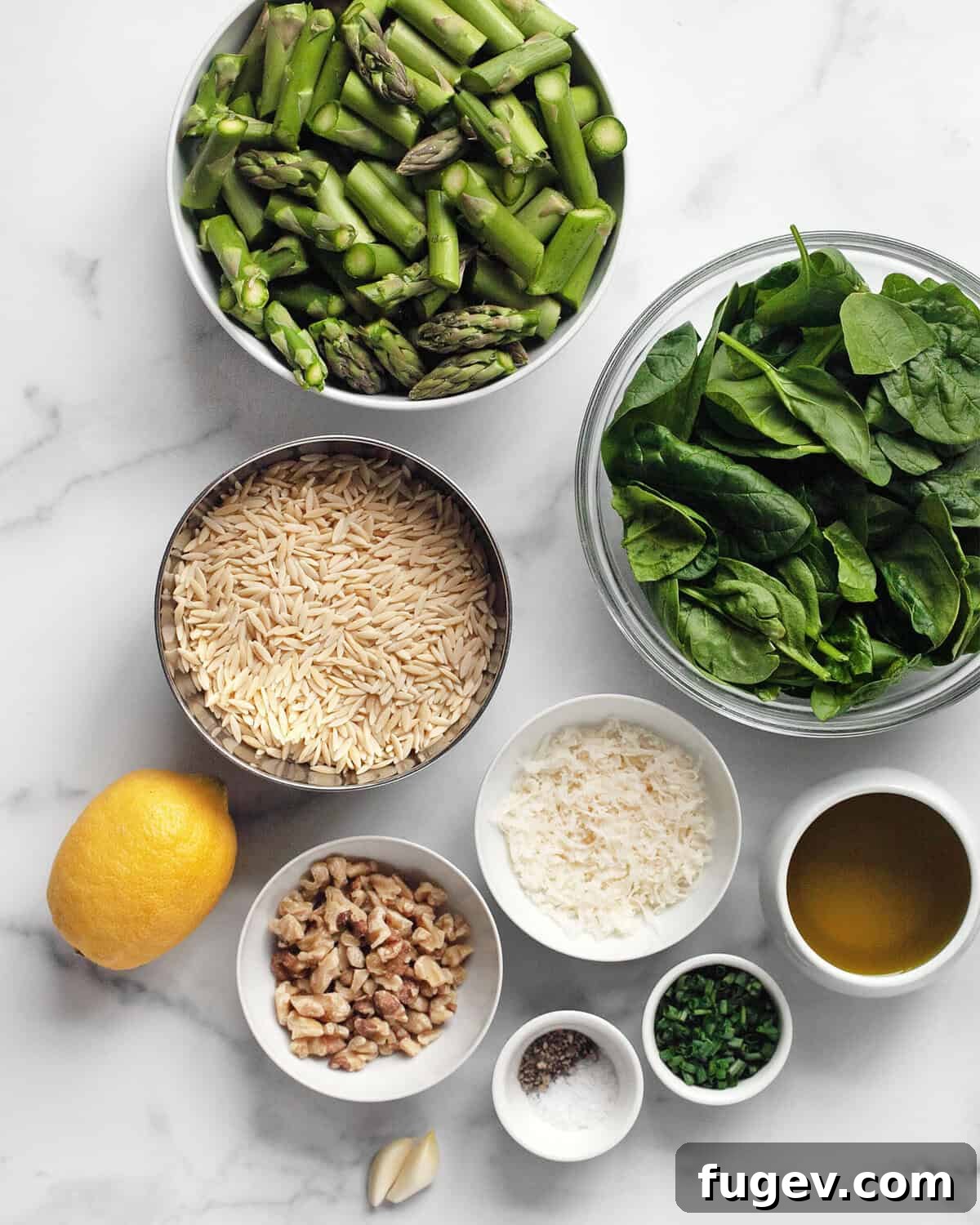 Vibrant Spinach Pesto Orzo with Roasted Asparagus 3 A flat lay of fresh ingredients for spinach pesto orzo, including vibrant green spinach, fresh asparagus, lemon, walnuts, Parmesan cheese, olive oil, and orzo pasta.
