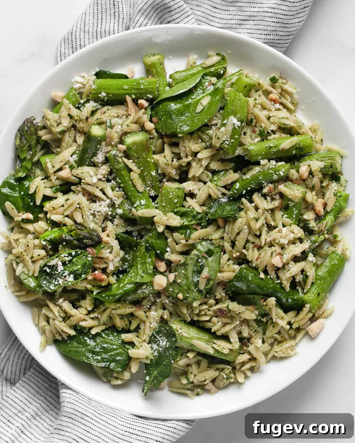 Vibrant Spinach Pesto Orzo with Roasted Asparagus 7 A generous serving of Spinach pesto orzo with roasted asparagus on a white plate, ready to be enjoyed.