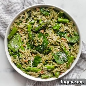 Spinach pesto orzo with roasted asparagus in a bowl.