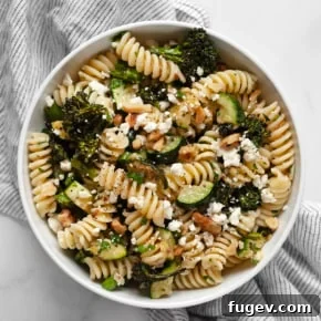Roasted broccolini and zucchini pasta salad with walnuts and feta on a plate, featuring vibrant green vegetables and a creamy dressing.