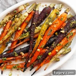Roasted rainbow carrots with vibrant green carrot top pesto on a serving plate, a colorful and fresh spring side dish.