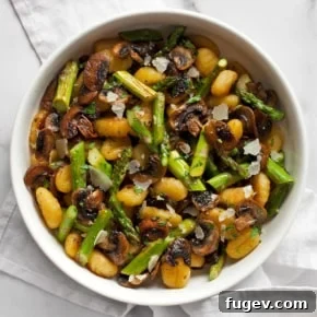 Roasted asparagus mushroom gnocchi served in a rustic bowl, showcasing a one-pan spring meal.
