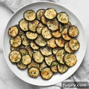 Parmesan roasted zucchini on a plate, showcasing golden-brown edges and a cheesy crust.